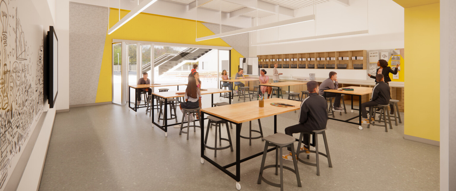 Classroom with yellow accents, light wood tables, and students interacting with their teacher