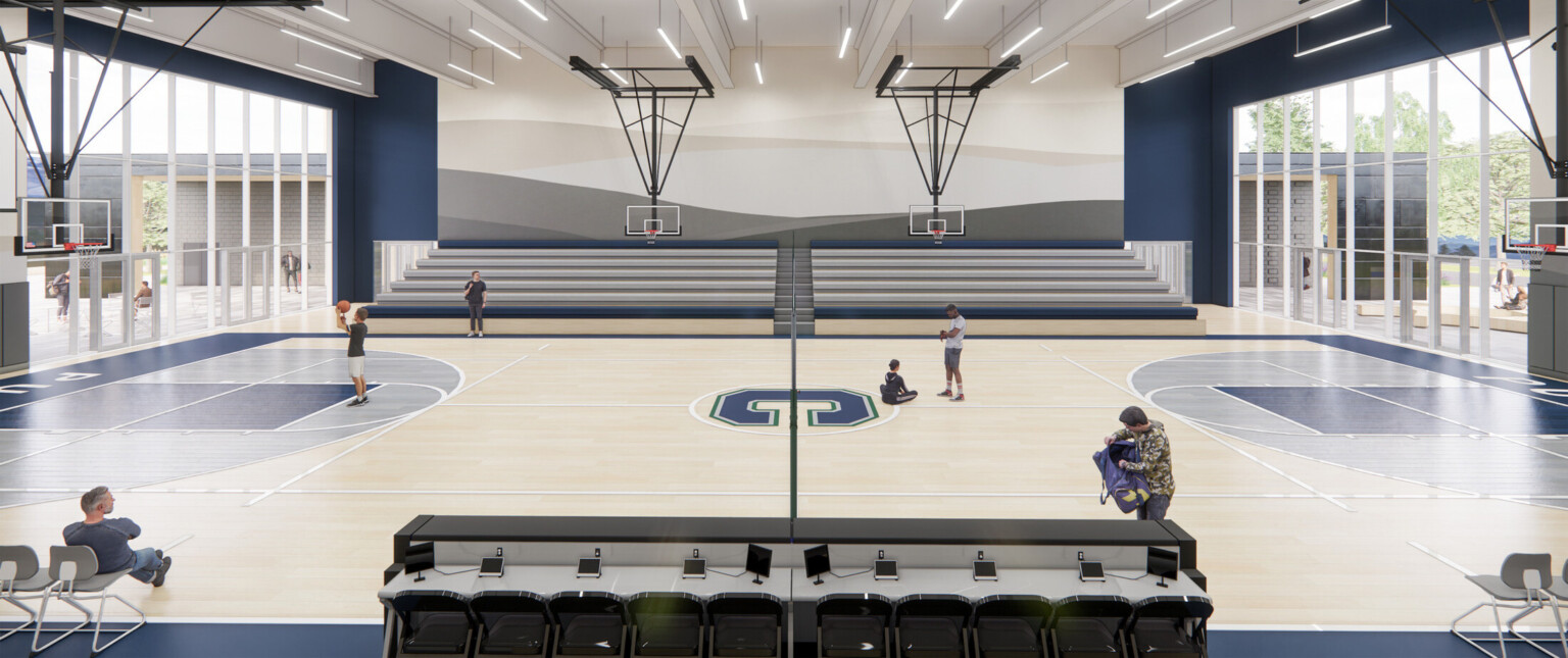 High school gym with light wood floors with blue accents with basketball goals suspended from the ceiling