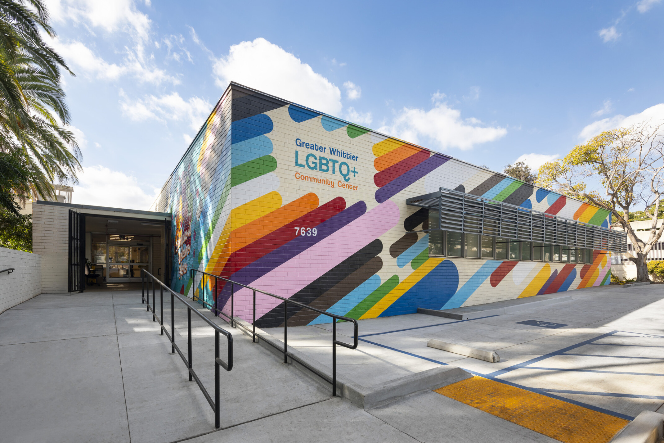 exterior of lgbtq+ center in california; colorful rainbow mural wraps the facade