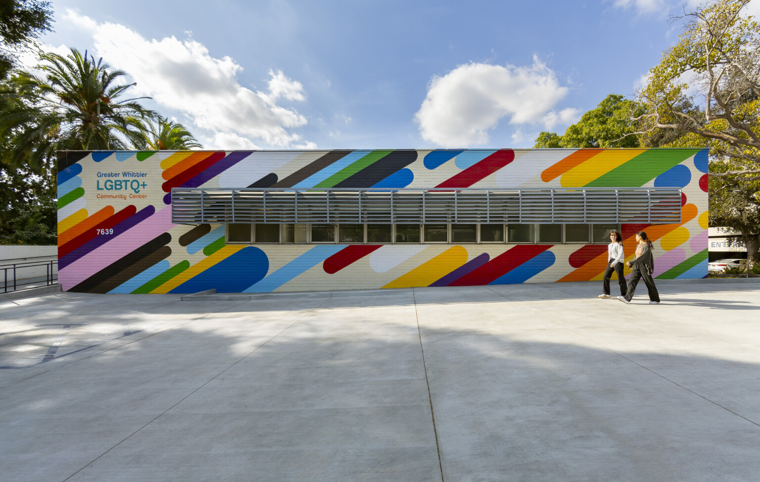 colorful one story building exterior with rainbow stripes and "Greater Whittier LGBTQ+ Community Center" sign