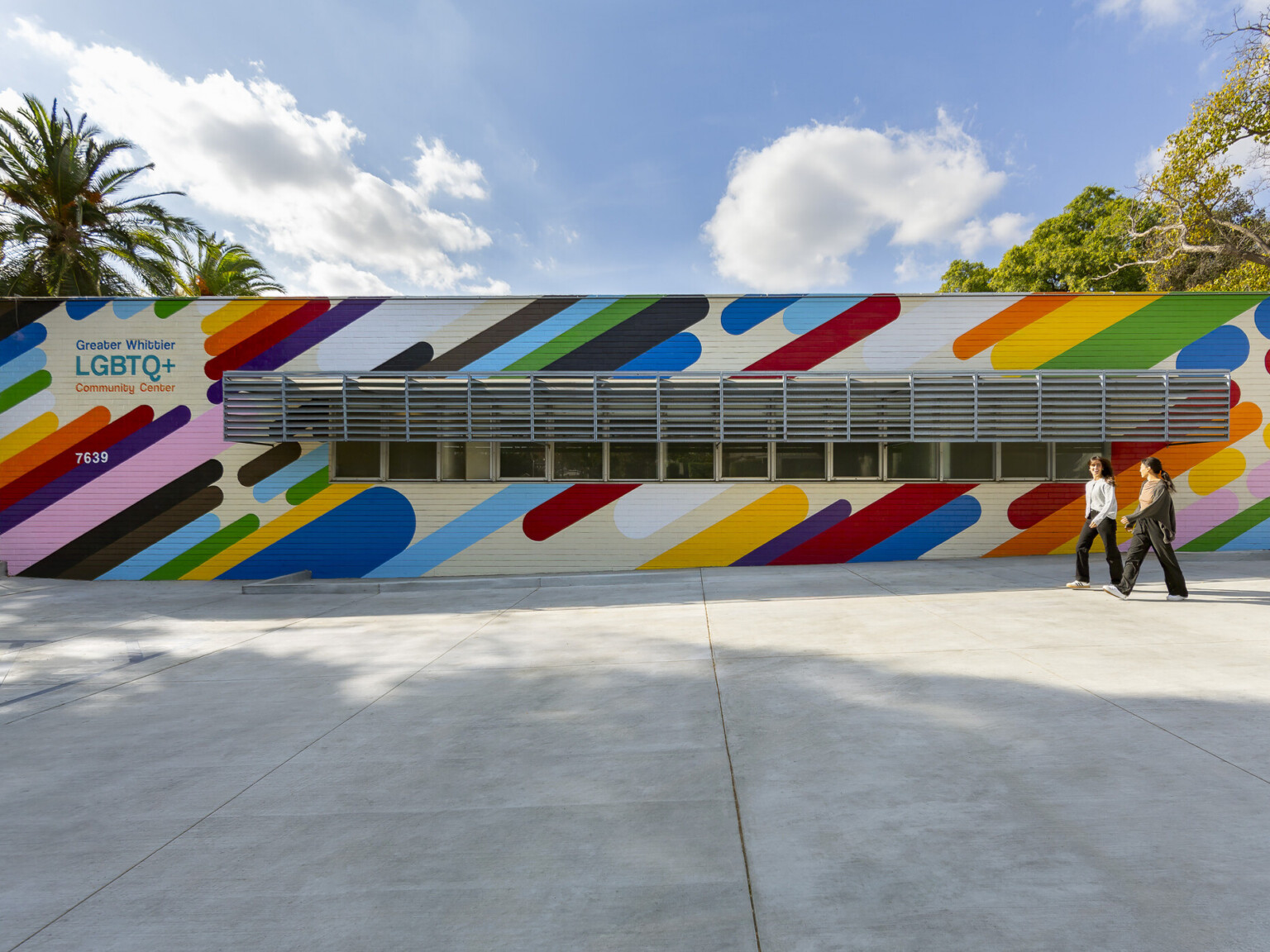 colorful one story building exterior with rainbow stripes and "Greater Whittier LGBTQ+ Community Center" sign