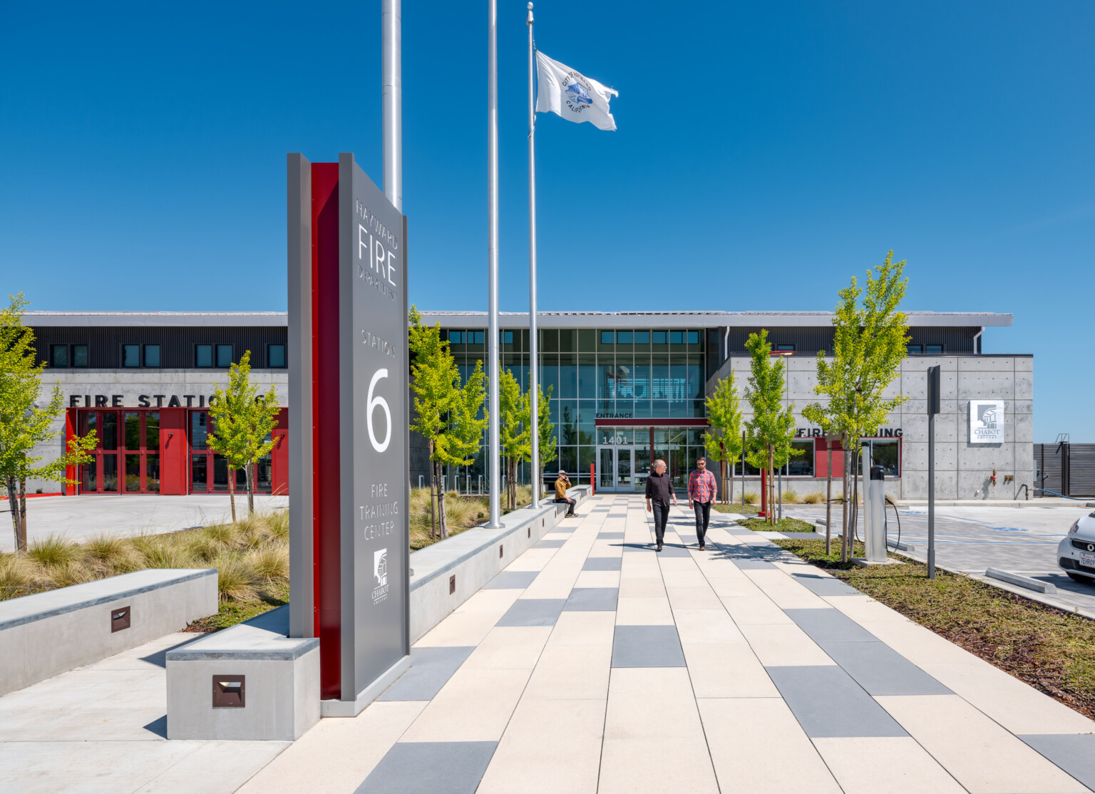 Exterior of the Hayward Fire Department building. Multistory grey building with red accents with a grey and white walkway leading to the front doors