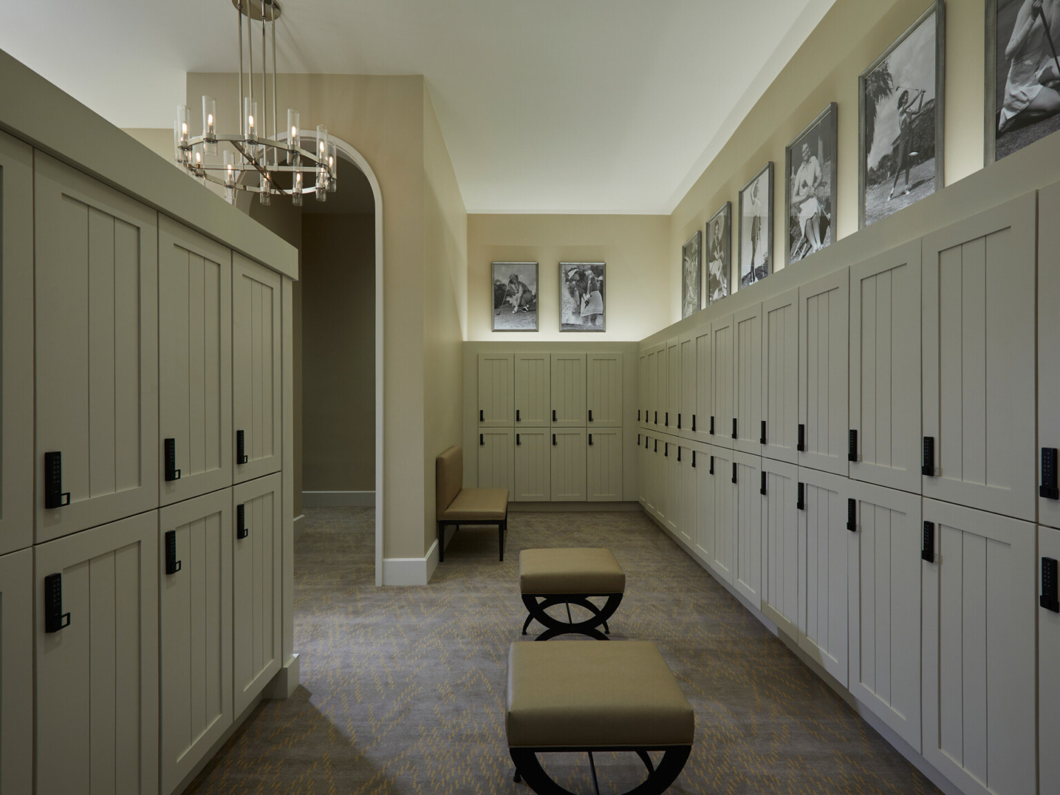 Locker room with beige lockers, black digital locks, photographs above, and benches in the center of the aisle
