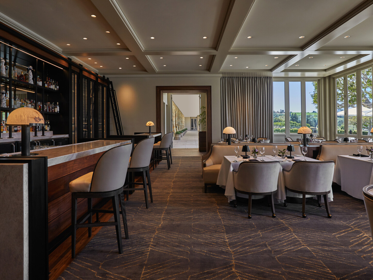 Elegant restaurant interior with a bar and dining area featuring large windows and scenic views