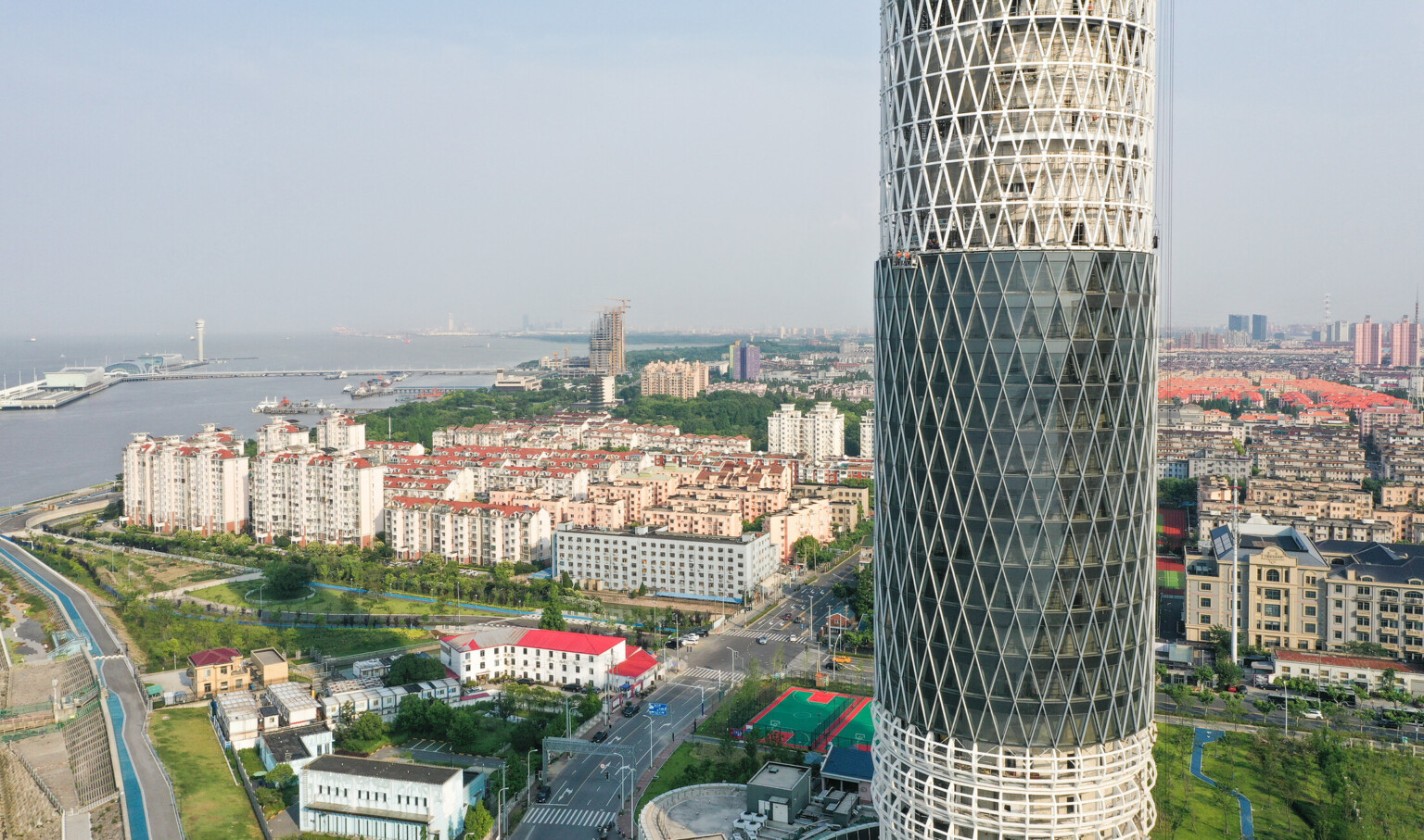 high rise tower with triangular windows from the sky view with the city and river bay in the background