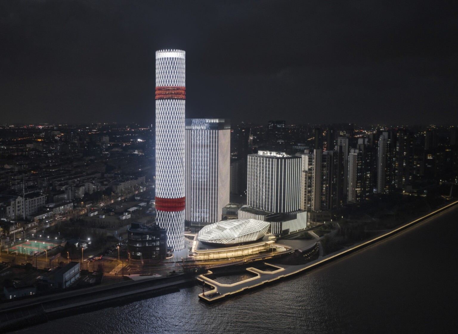 Baoshan Long Beach Complex illuminated at night along Shanghai's Yangtze River, diamond geometric light on cylindrical tower, locations