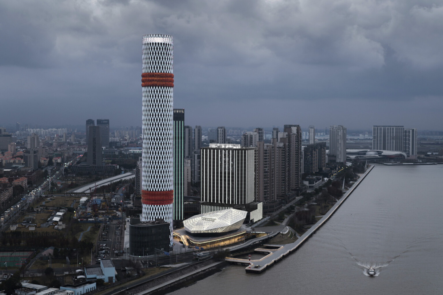 Baoshan Long Beach Complex illuminated at night along Shanghai's Yangtze River, diamond geometric light on cylindrical tower Baoshan Long Beach Complex illuminated at night along Shanghai's Yangtze River, diamond geometric light on cylindrical tower