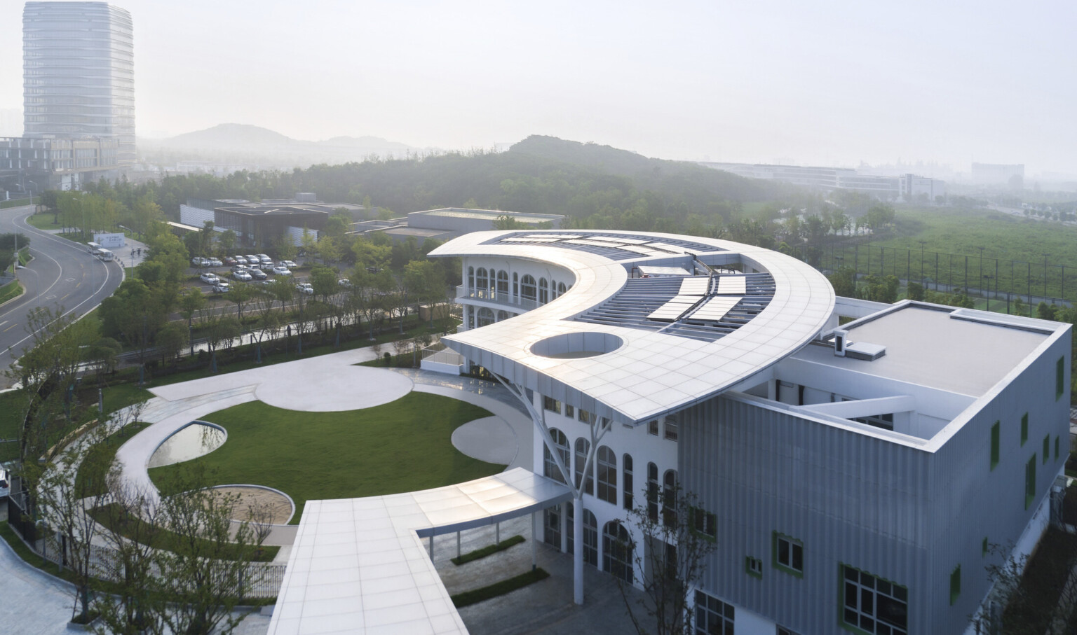Suzhou Greenshore LOT 16 Kindergarten, a white 3 story building with semi circular canopy and front facade facing green lawn