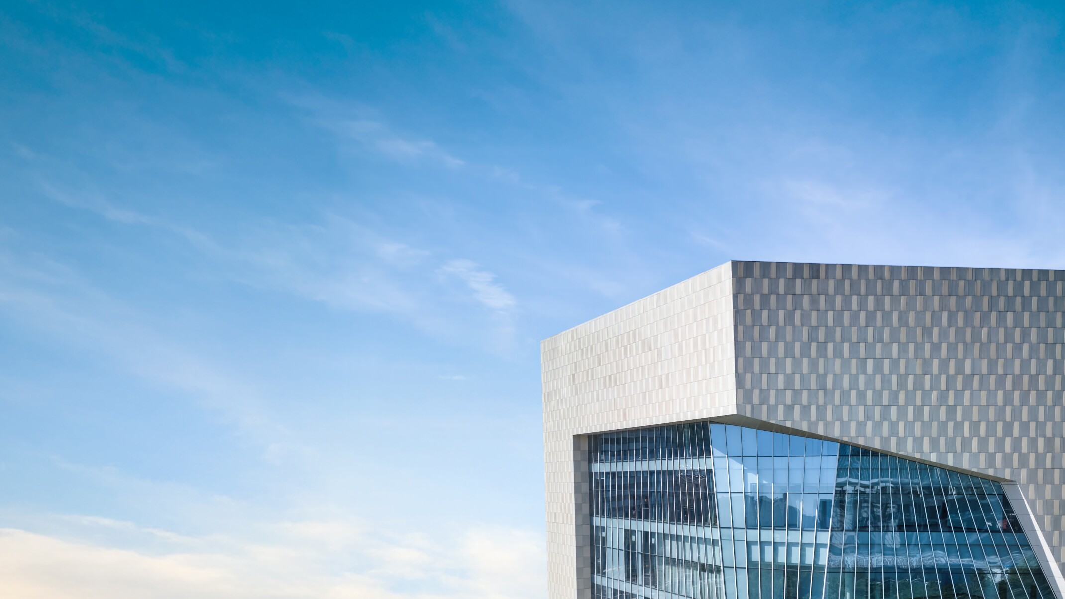 futuristic design of a building with a glass facade, grey metal facade, and geometric cuts, DLR Group 2024 Annual Report
