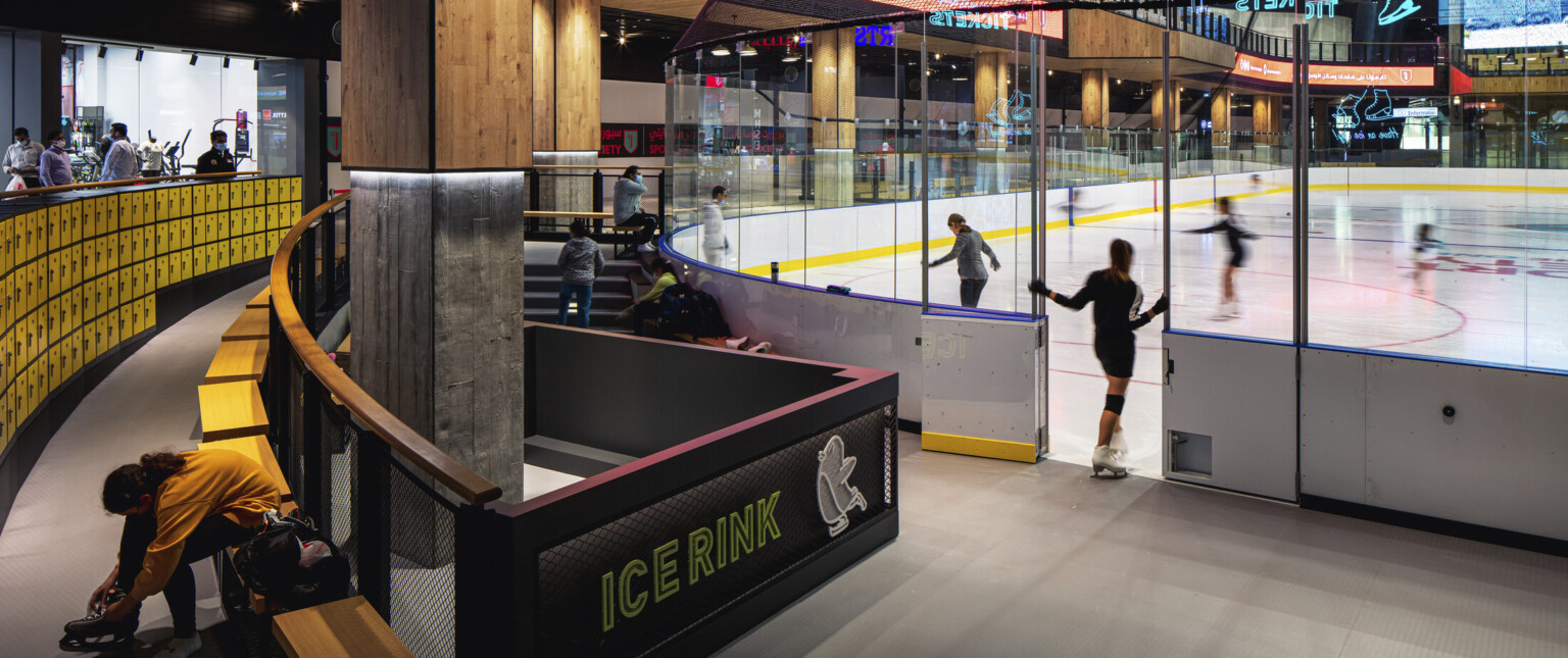 Ice rink showing the ice with an entry door surrounded by glass and yellow accents