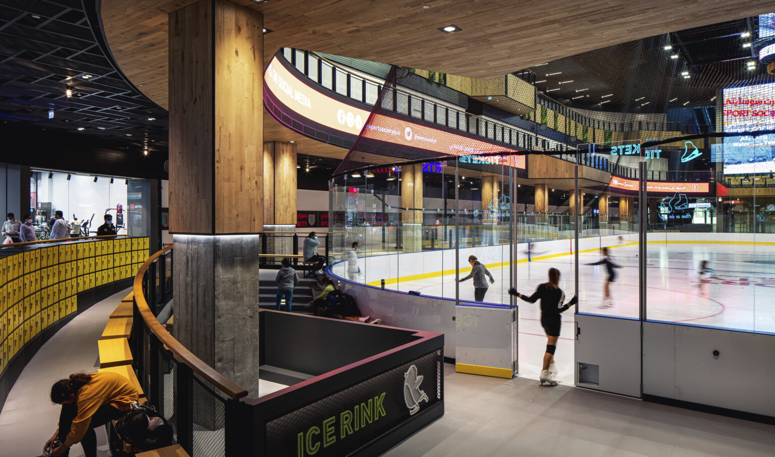 Indoor year-round ice rink in triple-height atrium, glass partitions, seating for watching and changing gear