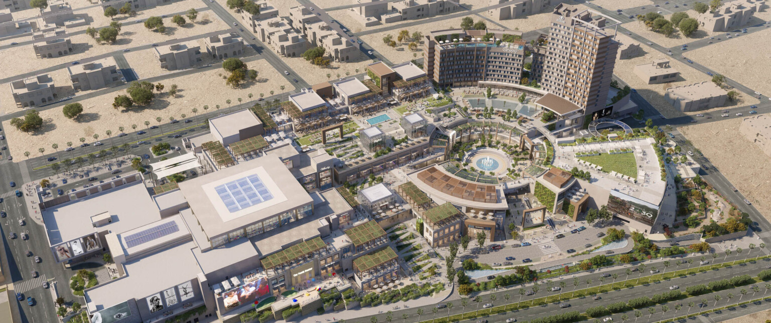 Aerial view of the campus plan built into a hill with rounded central courtyard lined with canopies, midrise buildings to left