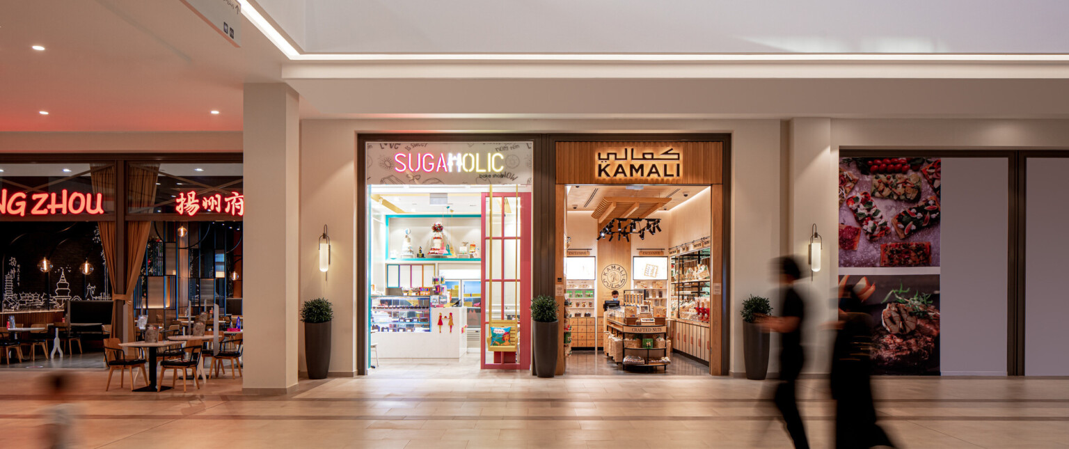 Interior of a shopping mall showing multiple store fronts with colorful signs