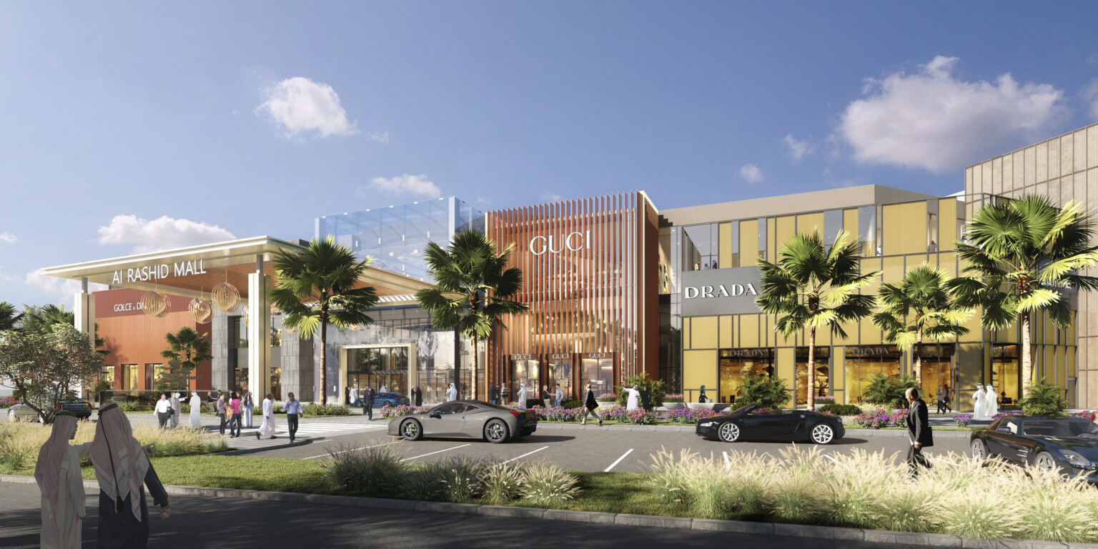 A mall exterior with cars and palm trees against a backdrop of sunny blue skies.