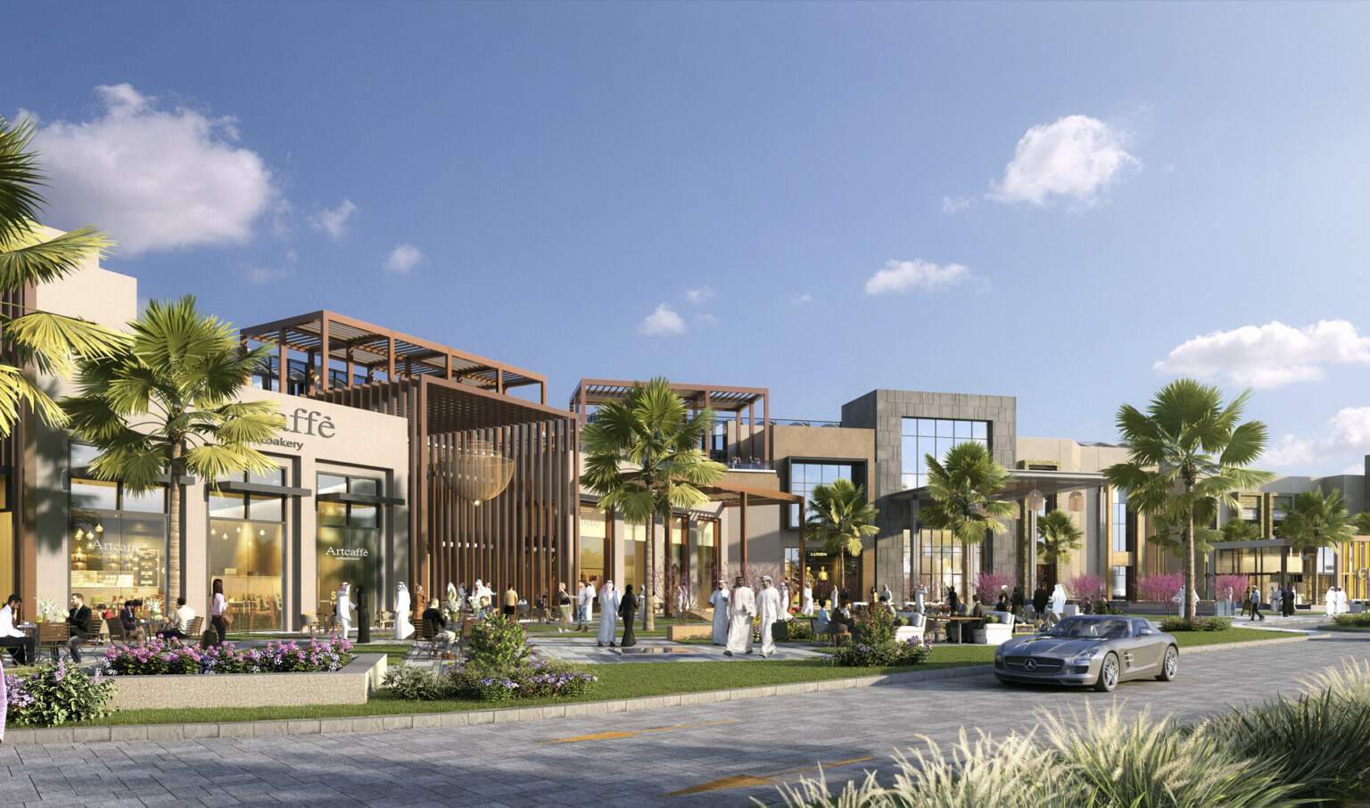 A mall exterior with cars and palm trees against a backdrop of sunny blue skies.