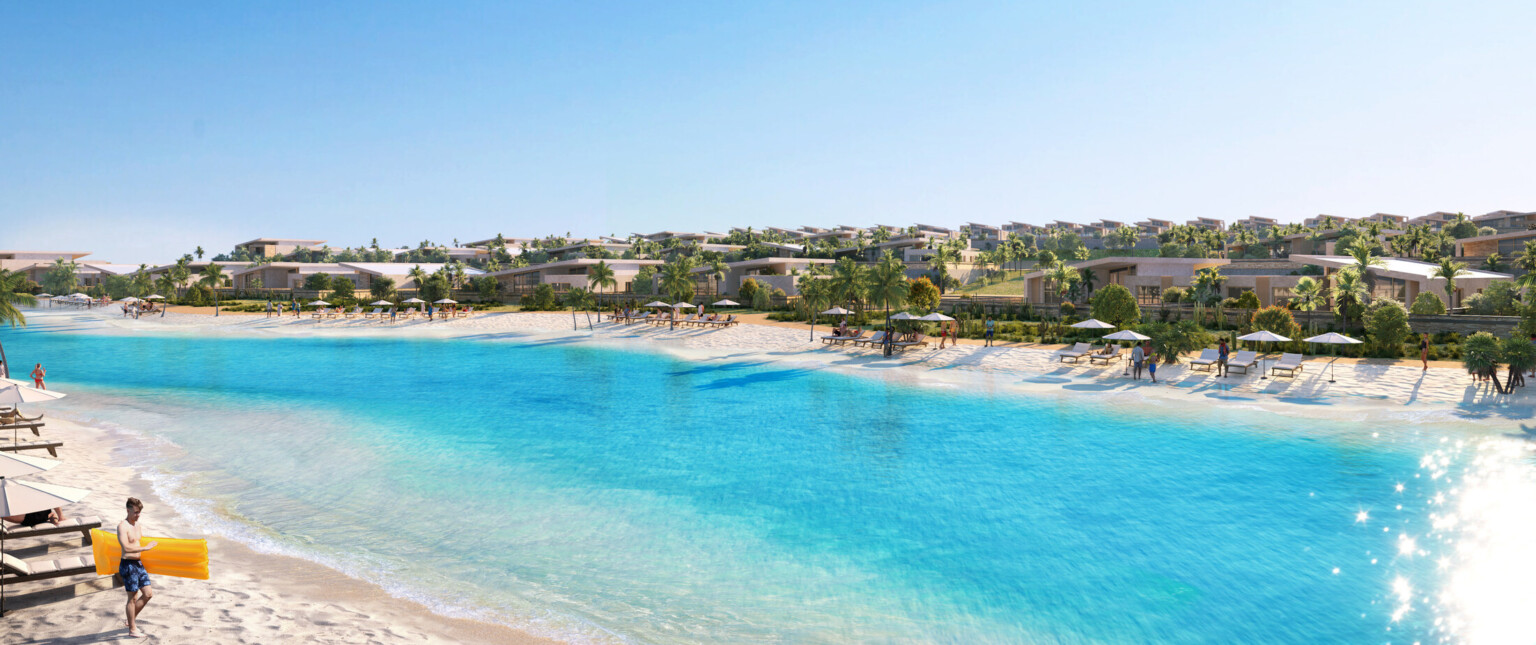 Aerial view of a beach front resort with white sand, blue water, and palm trees.