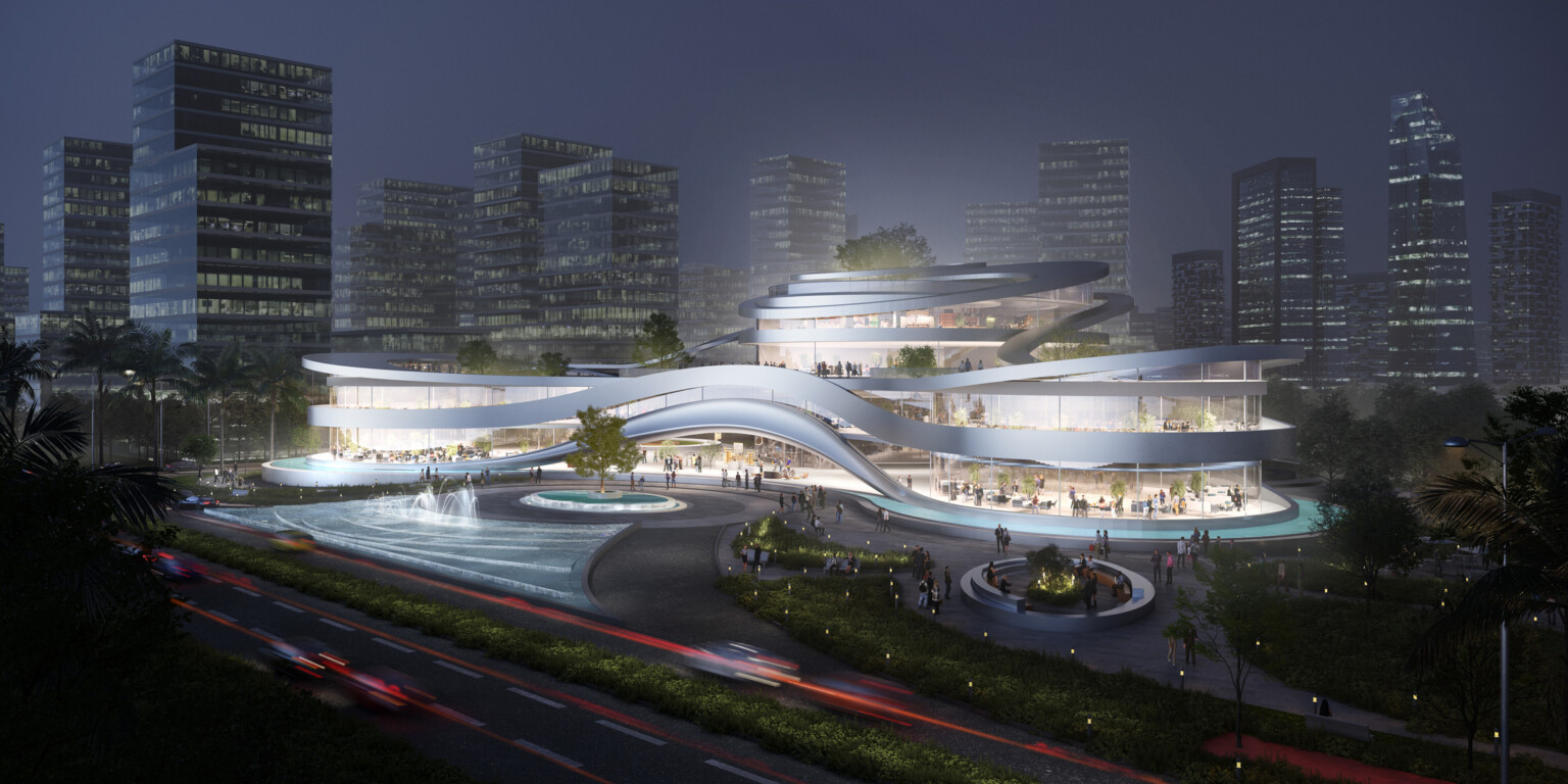 The building is illuminated, showcasing its sleek, modern architecture with large glass windows and terraces. Surrounding the center are landscaped gardens and water features, enhancing the aesthetic appeal.