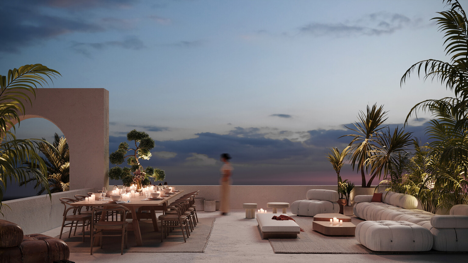 Late evening lit patio looking out to the sky; decorated with modern white and wood furniture; a large white couch on the right faces a large communal natural wood table' greenery featured on the peripheries of the image