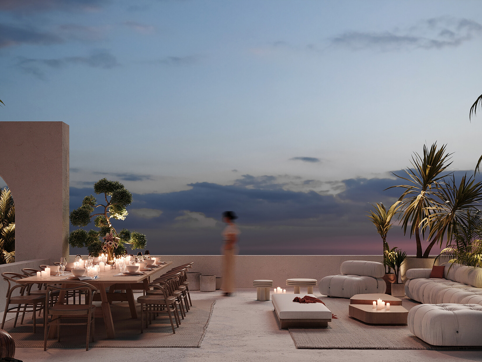 Late evening lit patio looking out to the sky; decorated with modern white and wood furniture; a large white couch on the right faces a large communal natural wood table' greenery featured on the peripheries of the image