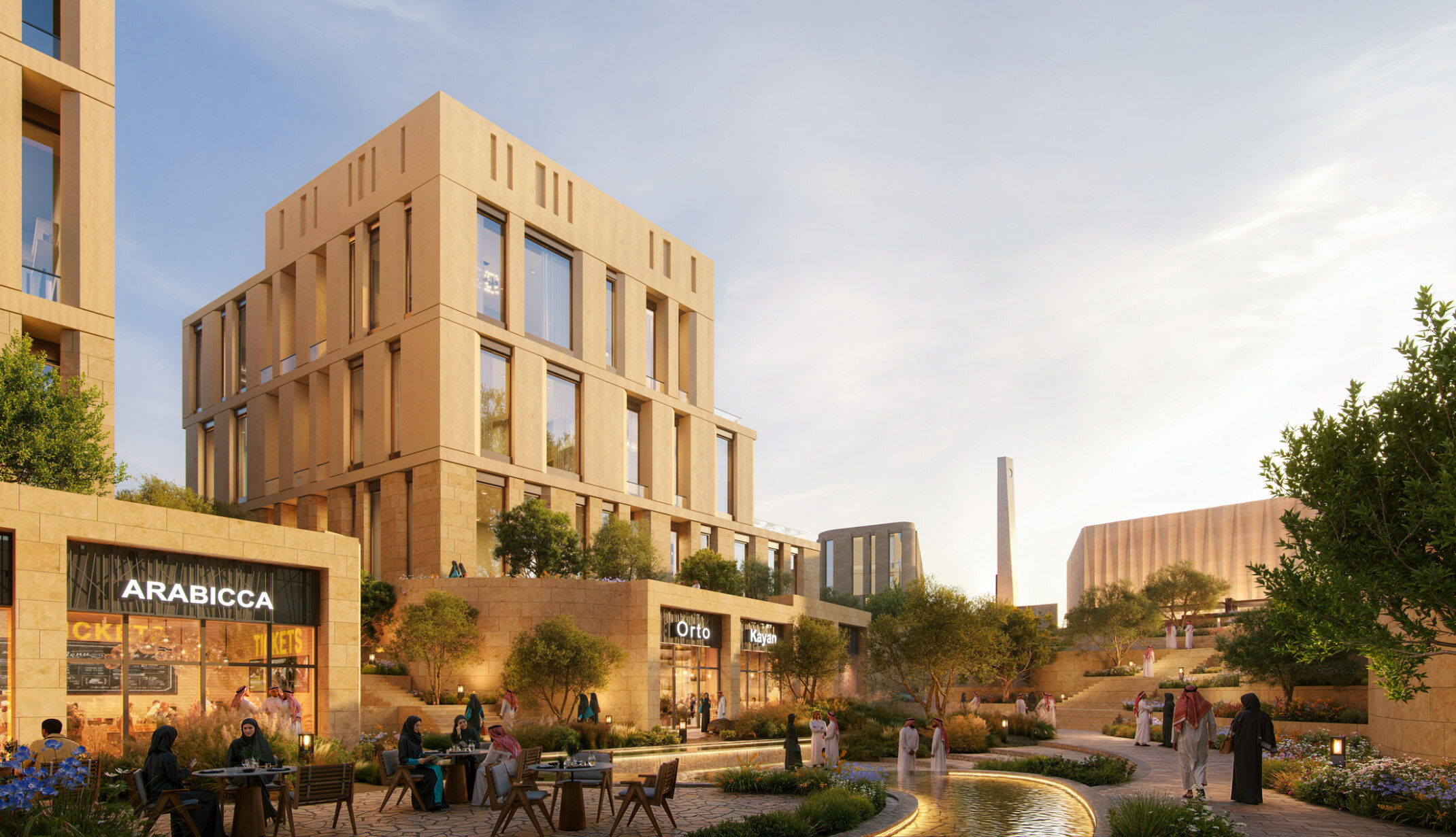Street-level view of LIWAN Najd in Riyadh, showing the wadi-side public realm with landscaped pedestrian paths, water features, outdoor dining, retail frontages, and the mosque and minaret beyond.