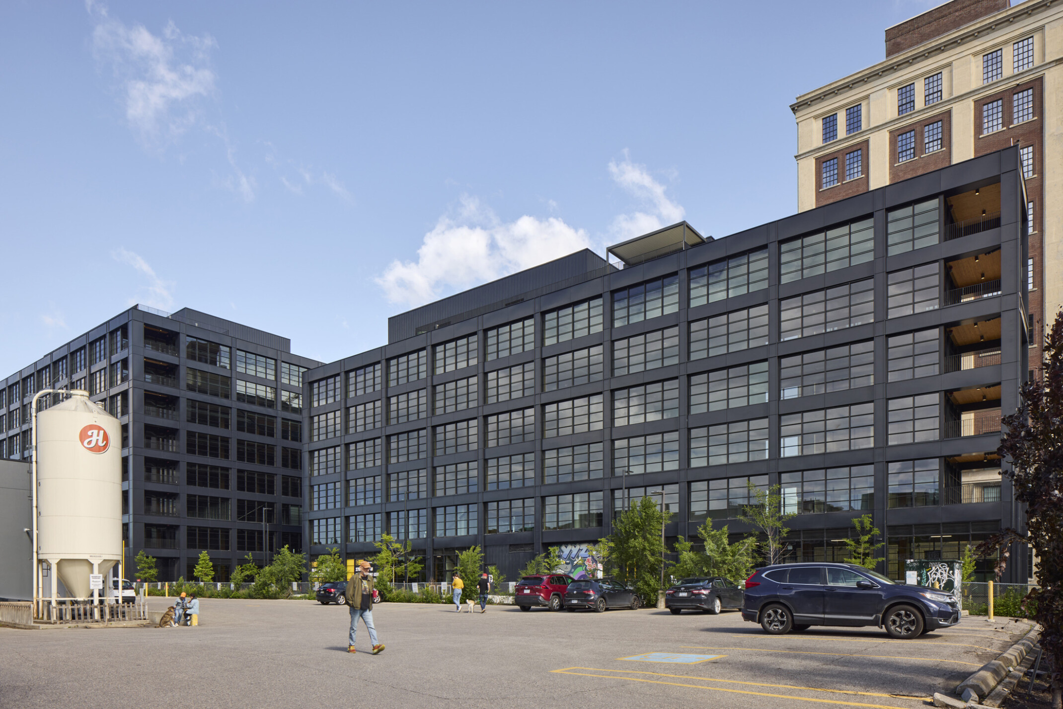 Black multistory office building filled with windows in front of a larger multistory office building