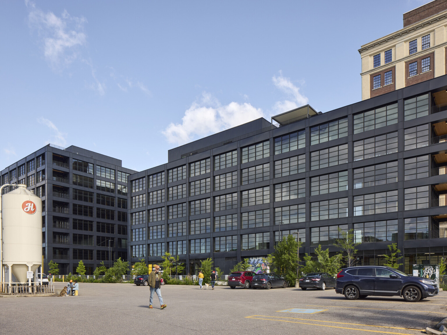 Black multistory office building filled with windows in front of a larger multistory office building