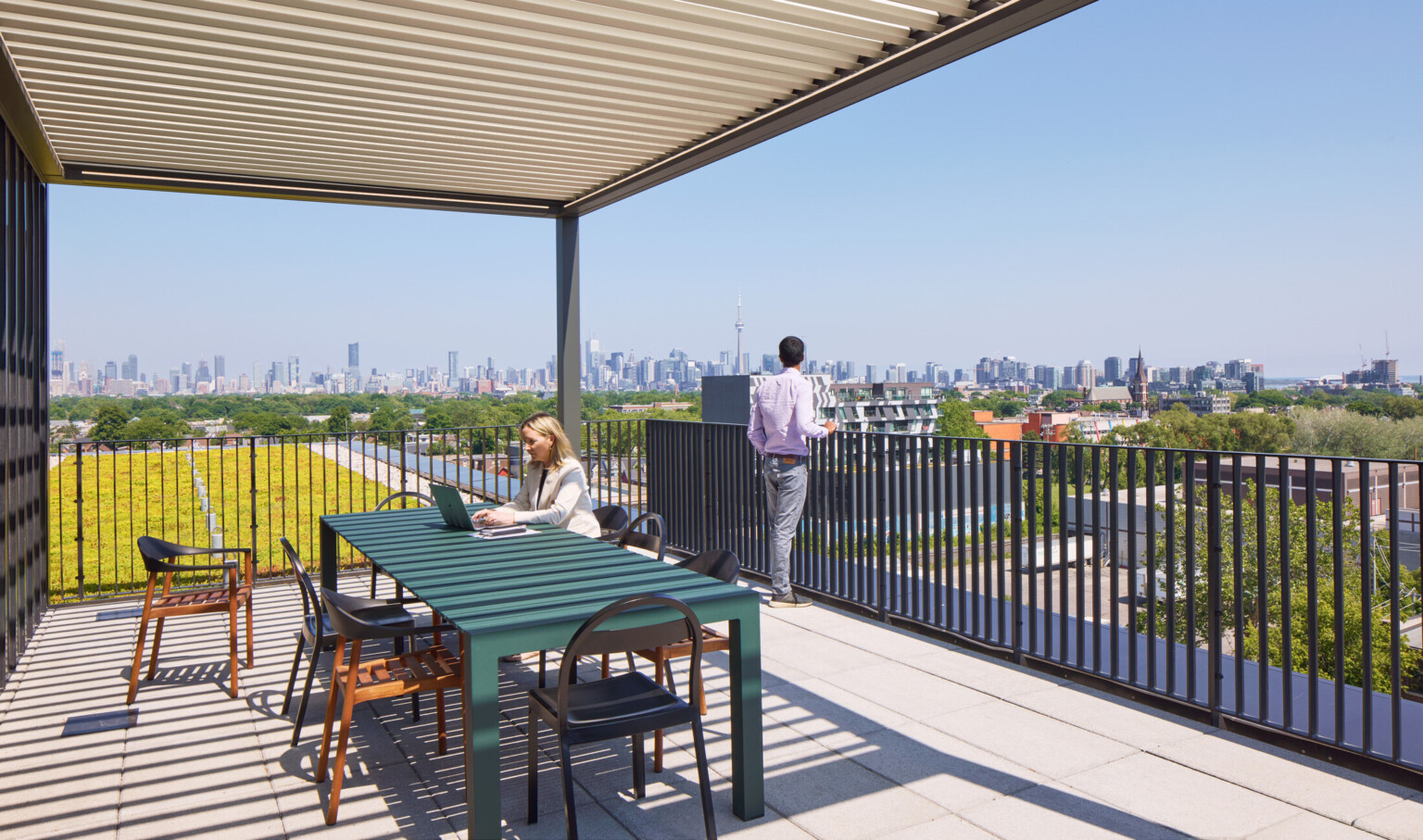 Outdoor seating area on a balcony overlooking a downtown skyline filled with large buildings.