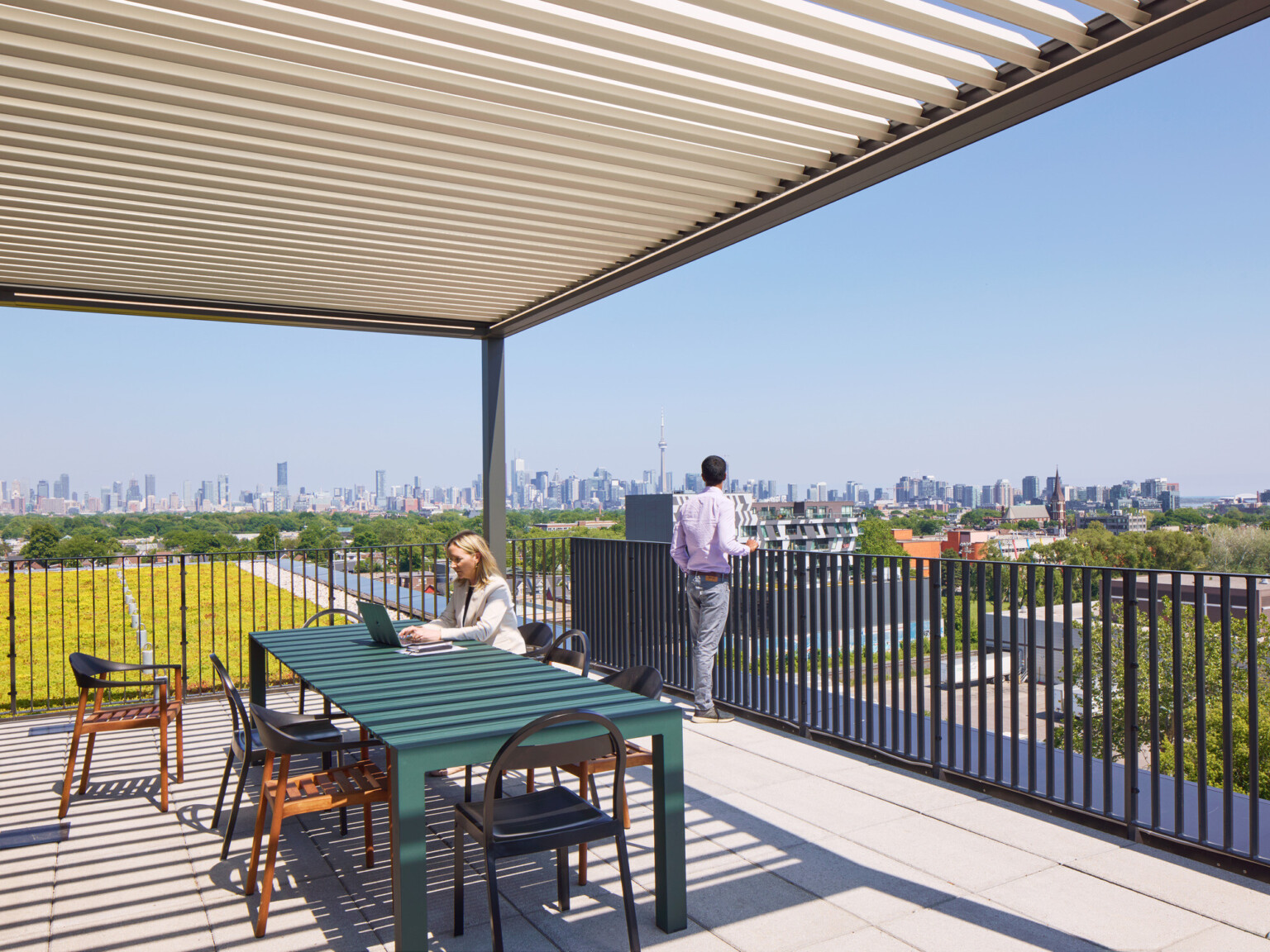 Outdoor seating area on a balcony overlooking a downtown skyline filled with large buildings.