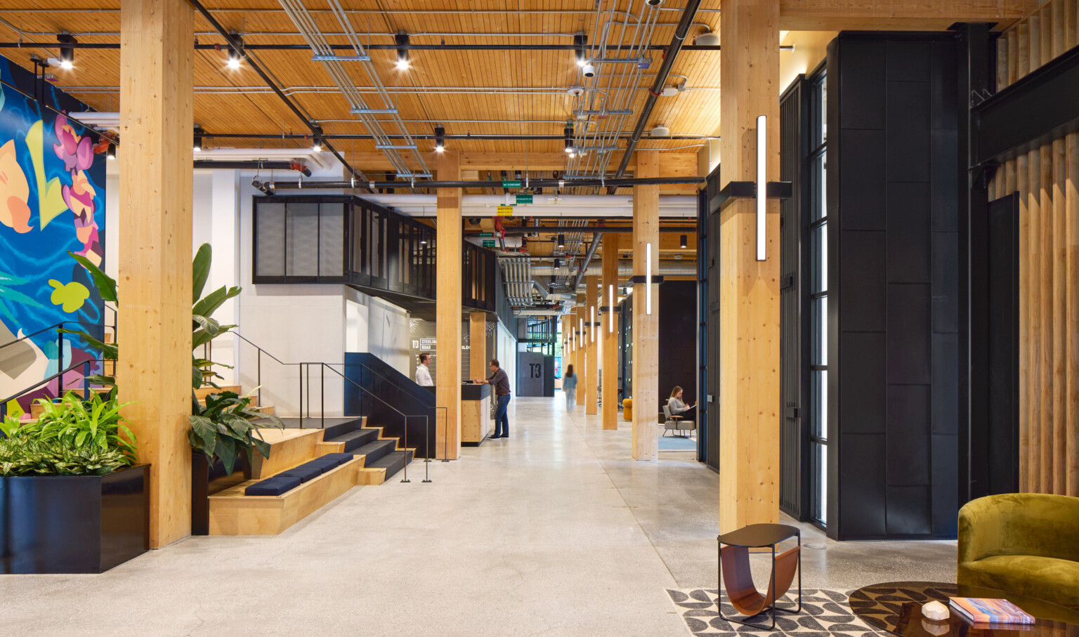 Office hallway with exposed wooden beams, colorful wall mural and black accents throughout