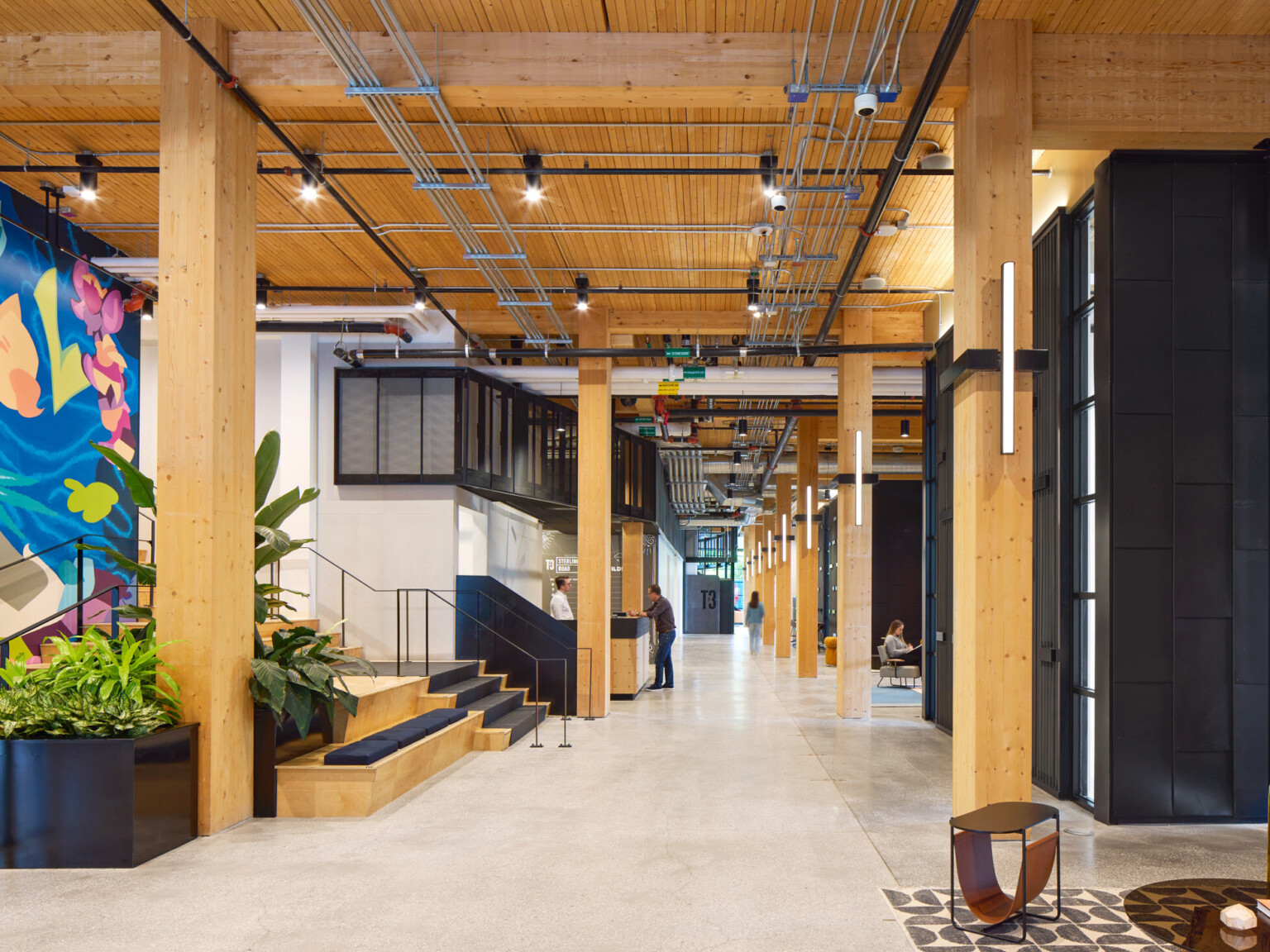 Office hallway with exposed wooden beams, colorful wall mural and black accents throughout