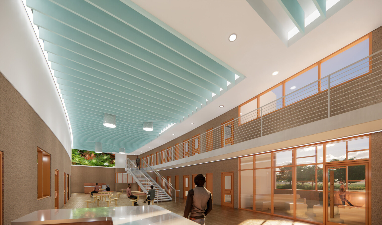 Large communal area in a corrections facility with high ceilings, skylights, meeting tables, a second-floor walkway, and staff counter.