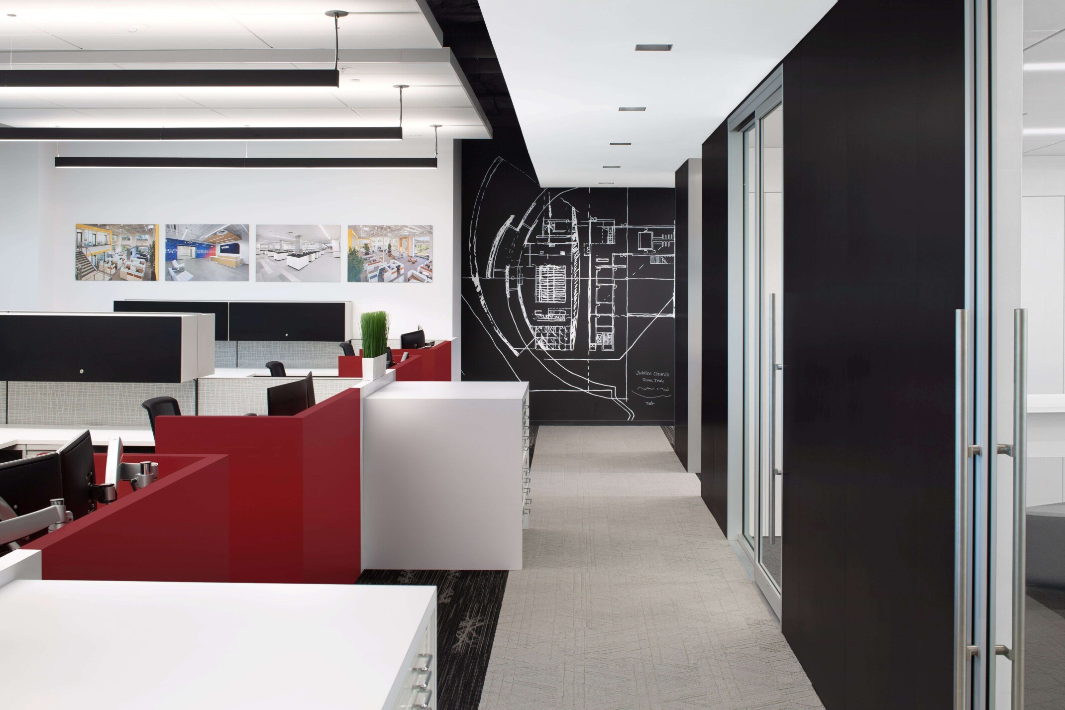 modern office hallway heading toward feature graphic art wall; black and white color scheme with pops of red in the left-hand cubicle section