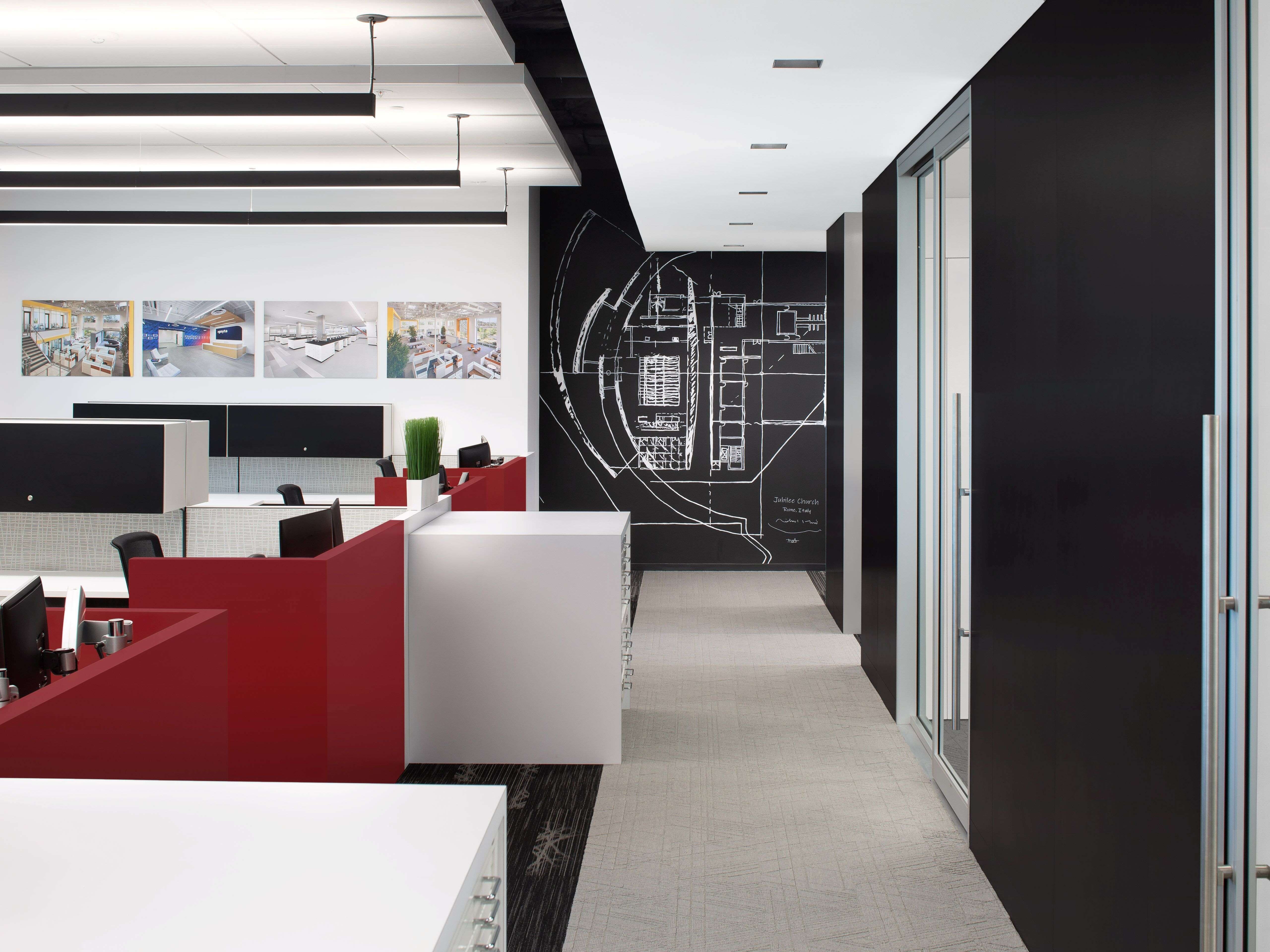 modern office hallway heading toward feature graphic art wall; black and white color scheme with pops of red in the left-hand cubicle section