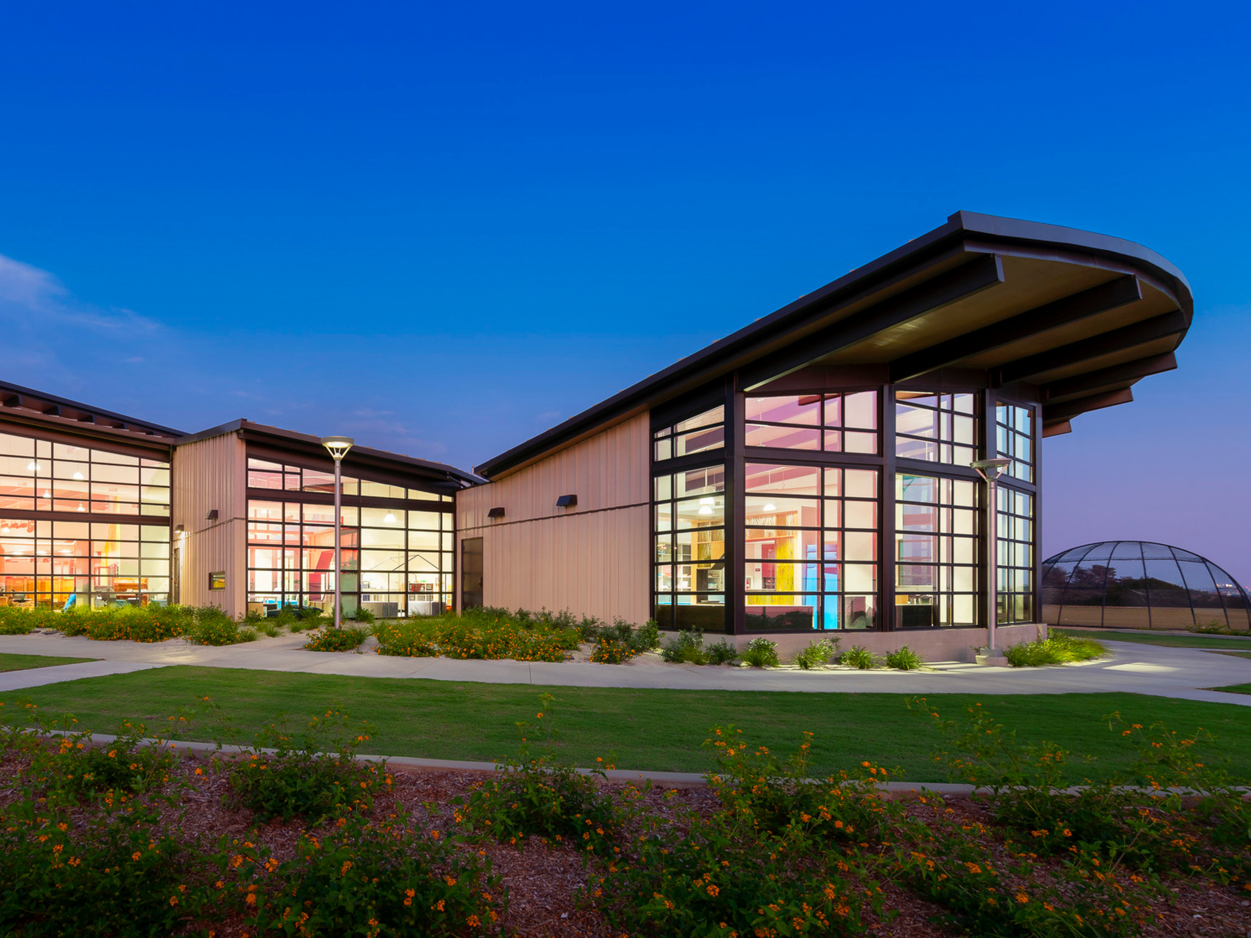 exterior of Del Mar Heights School at night, architecture inspired by California Coastal Architecture; indoor outdoor learning space with large openable windows