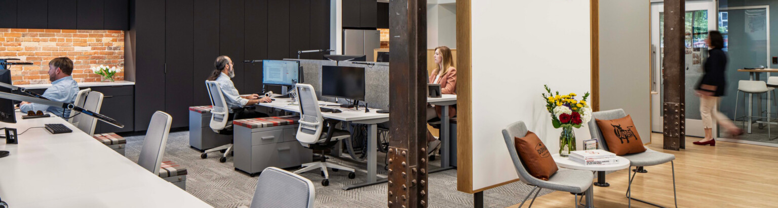 modern office with cubicles and a small seating area in front; DLR Group Durham office
