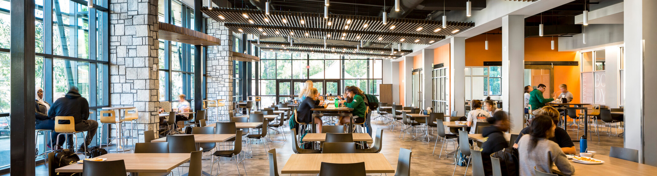 major collaboration space with low-top and high-top tables in a brightly, naturally lit building
