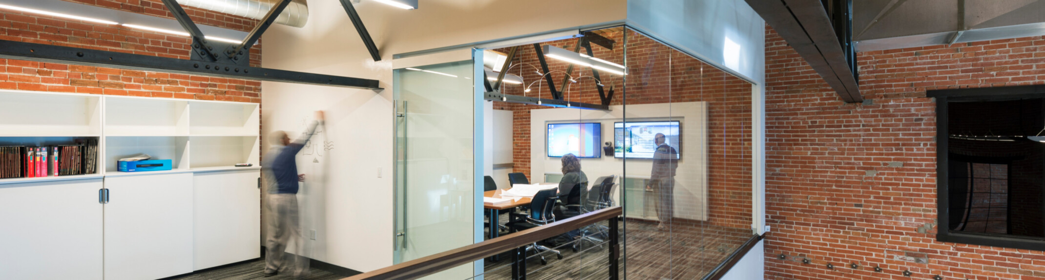 modern office space featuring a double height collaboration and desk space; people collaborating in rooms; DLR Group Colorado Springs office