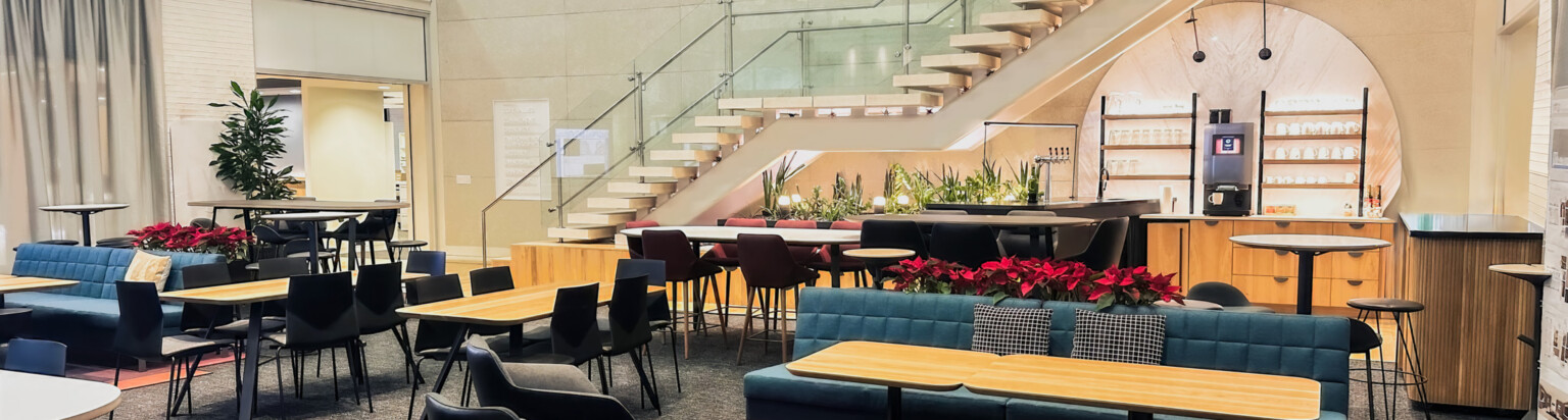 modern office collaboration and lunch center with staircase upstairs in background; DLR Group Minneapolis office