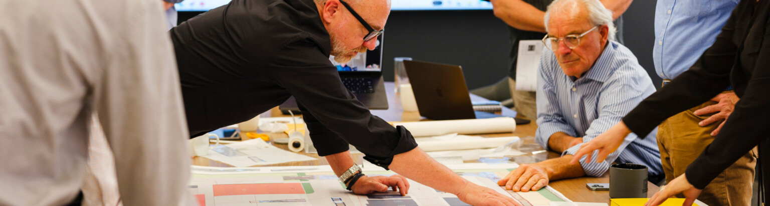 people collaborating over a schematic design at a table; DLR Group San Francisco office