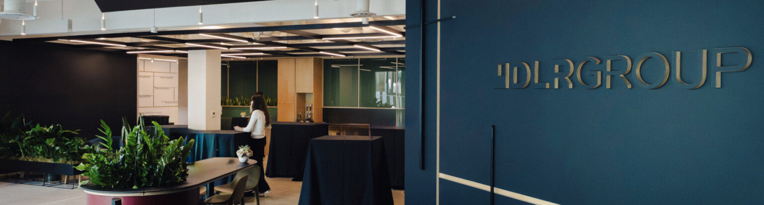 Modern office front entrance with a dark blue wall "DLR Group" opening to modular seating area; DLR Group San Diego office