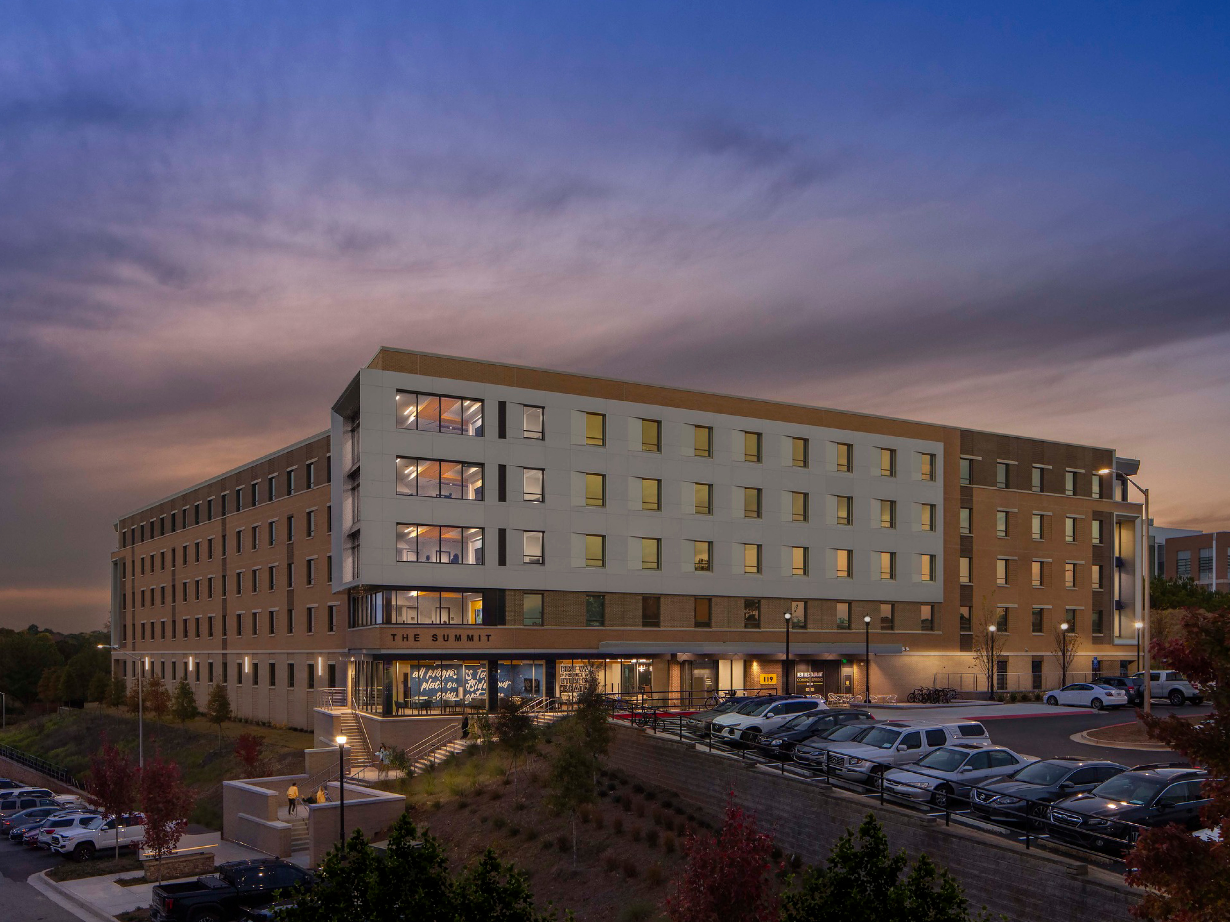 modern building against a sunset sky; tan building with lots of windows and a white exterior build out