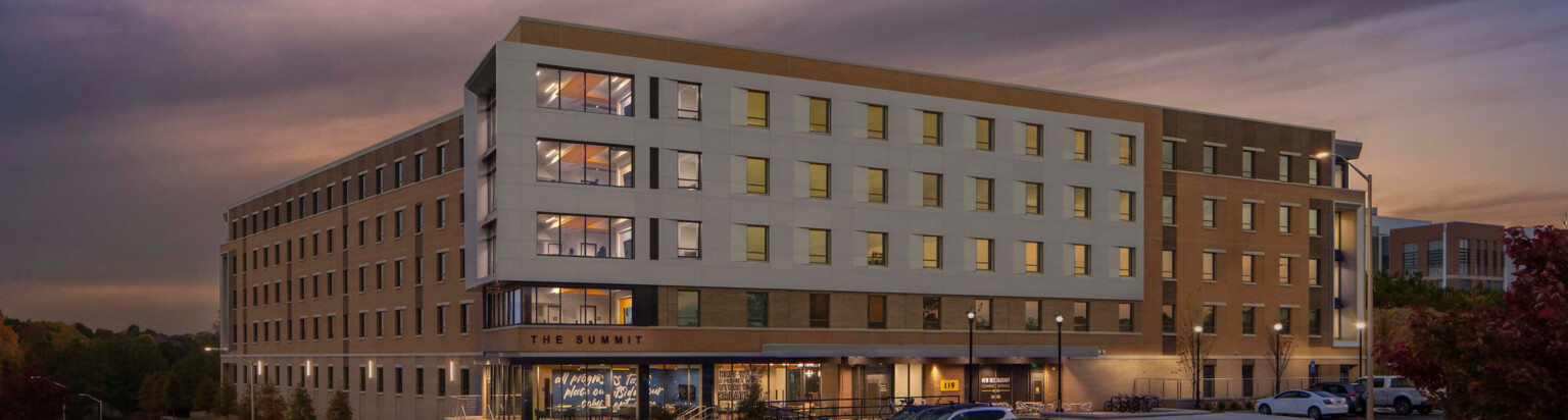modern building against a sunset sky; tan building with lots of windows and a white exterior build out