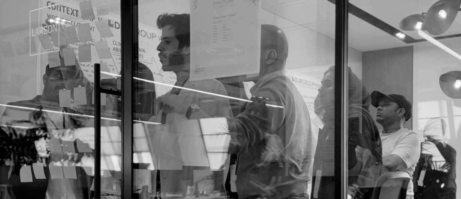 People standing in front of a glass wall drawing and collaborating