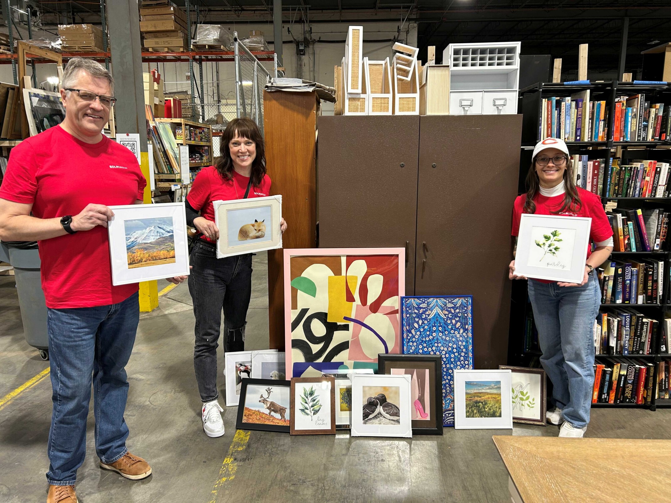 DLR Group employees stand with framed artwork in a warehouse