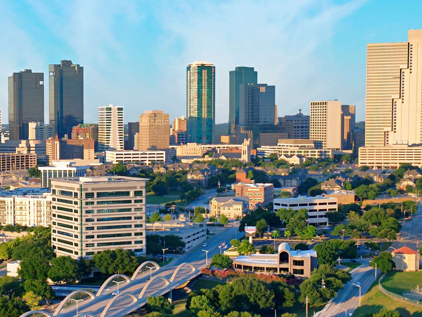 aerial view of the skyline of Fort Worth, Texas; a river winds around the city with skyscrapers and greenery in view