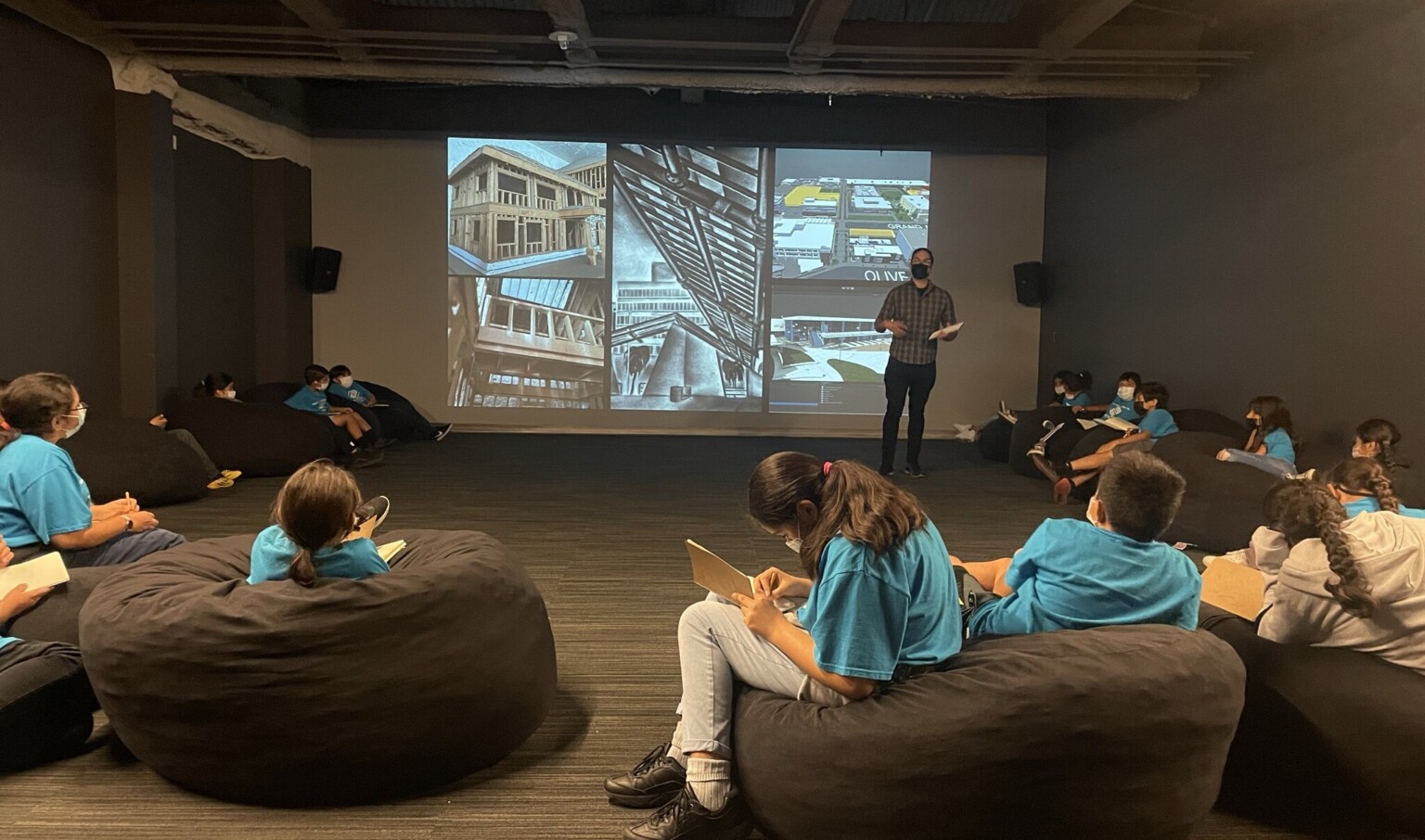 students sitting on beanie bags watching a projection on the far wall depicting architecture