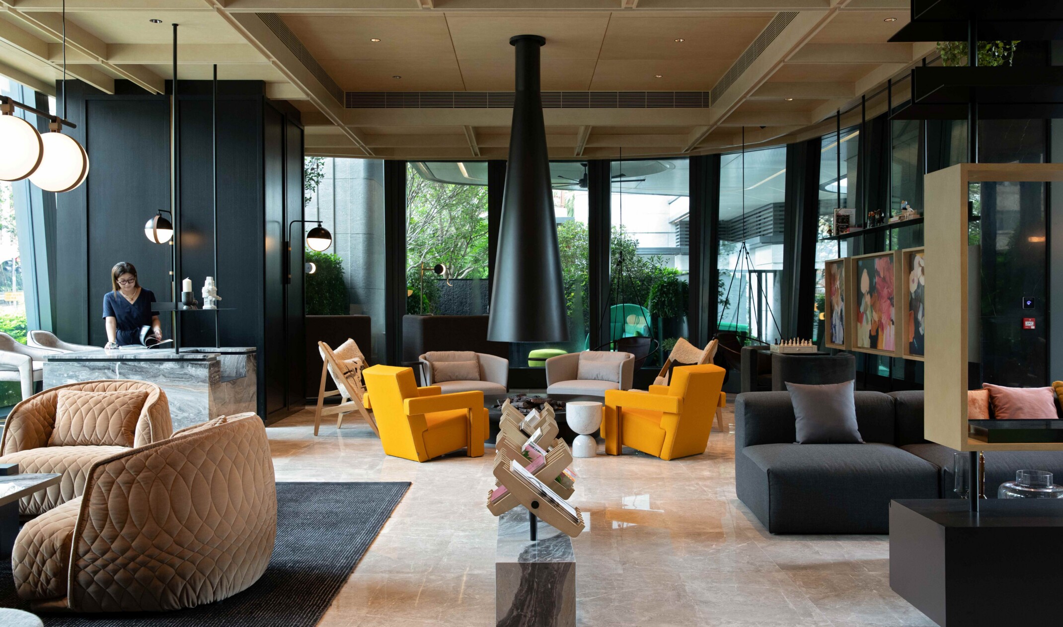 Modern amenity space with varied seating throughout the space; marble structure and artwork line the naturally-lit space