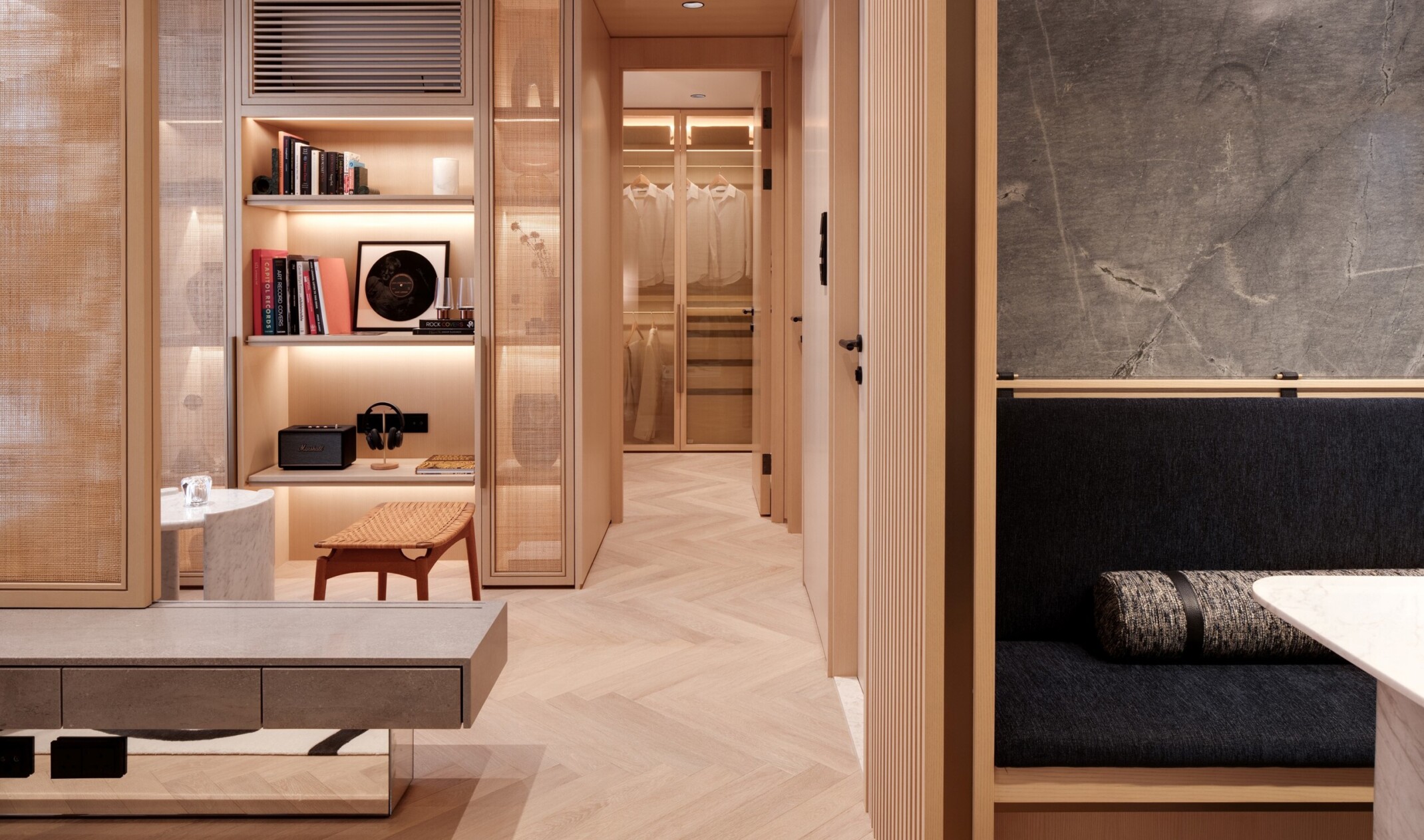 Lightwood closet space in a luxury, modern residential space; shelves with books and music elements for art; background built in shelving and hanging space