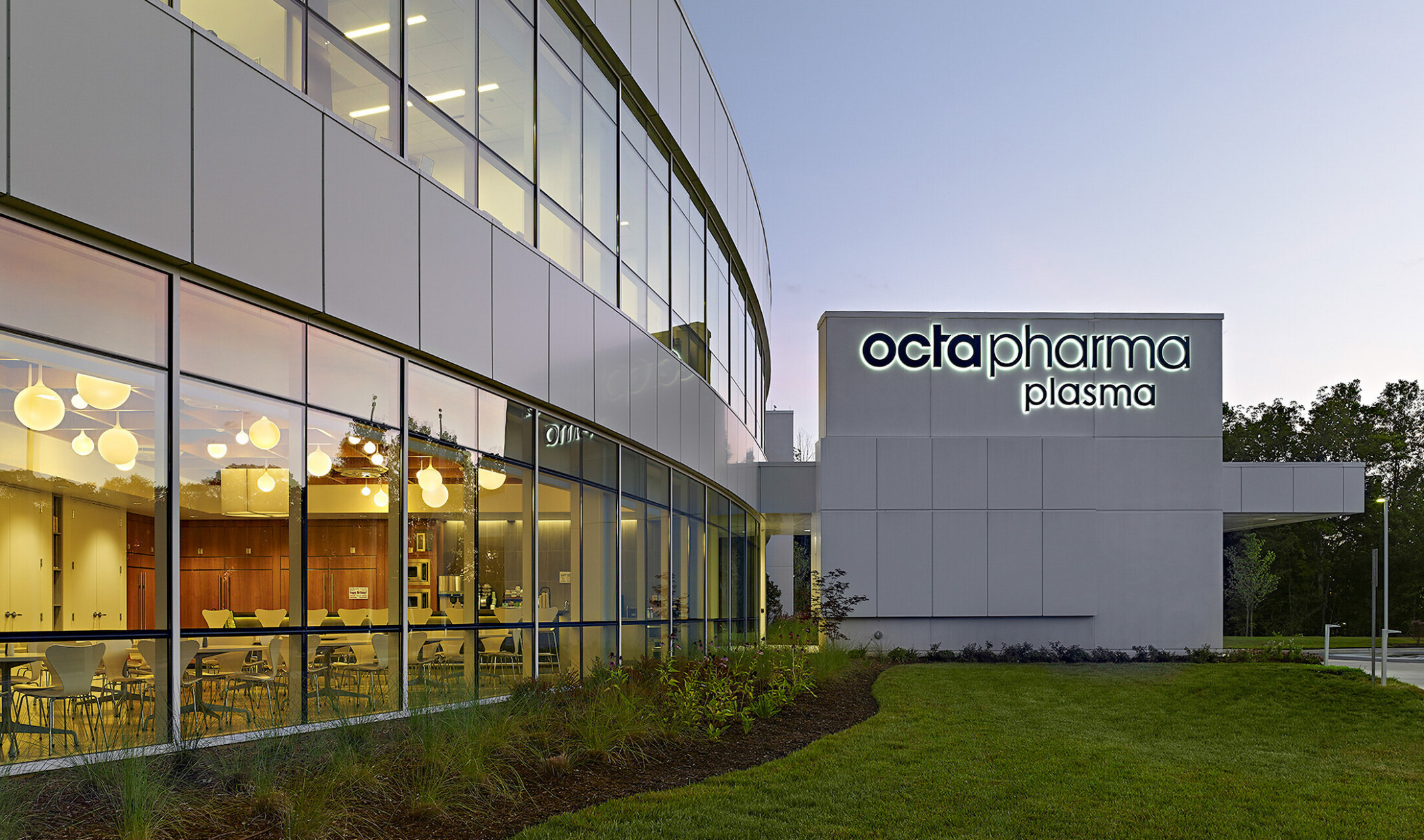 evening view of a double height glass facade with Octapharma logo on the far building wall