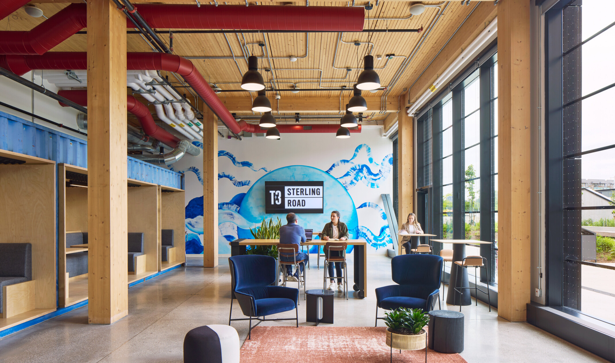 Mass timber interior with exposed wood and large windows, blue mural on back wall with Hines T3 Sterling Road signage